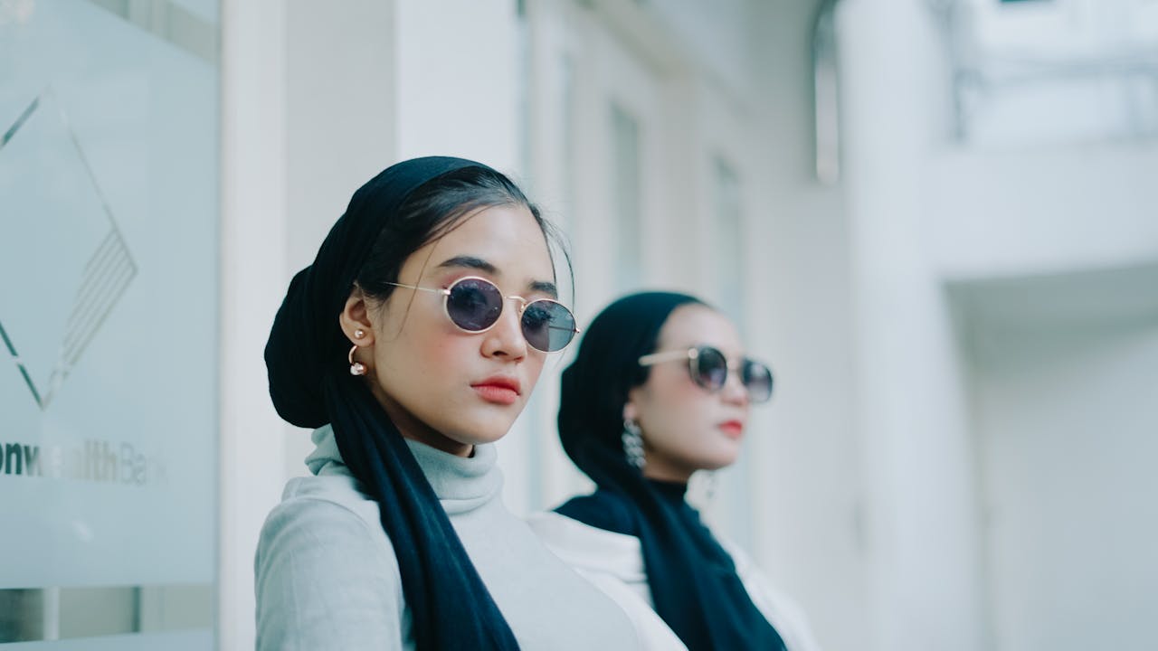 Services Stylish women wearing hijabs and sunglasses in a modern urban setting in Indonesia.